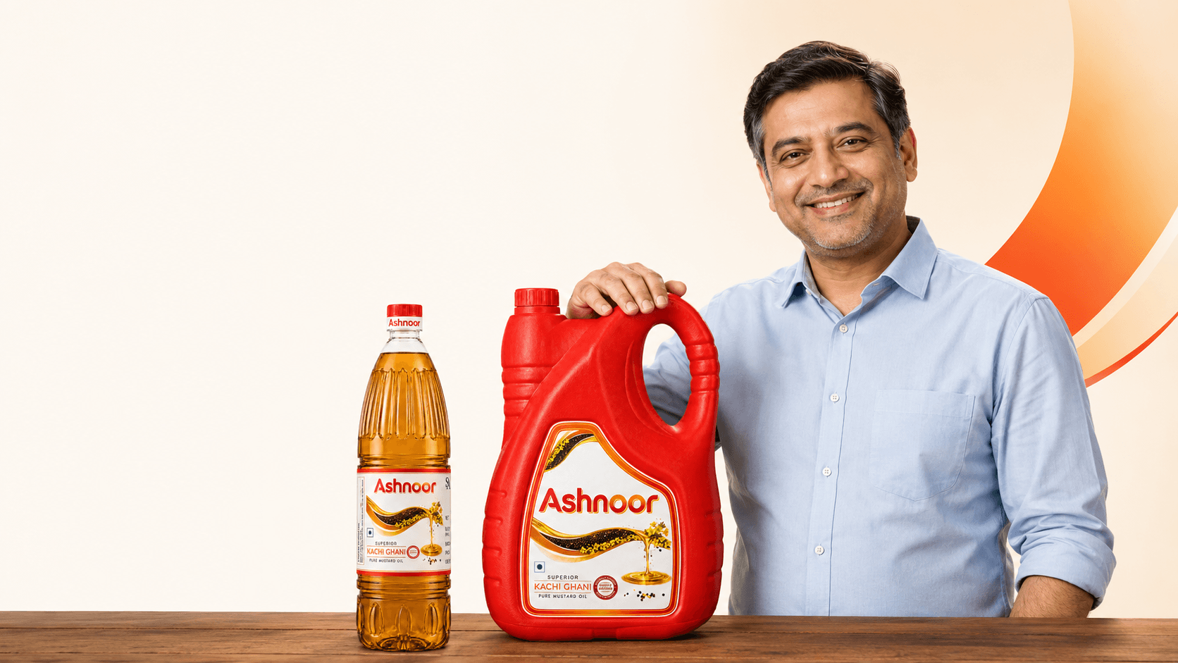 Ashnoor mustard oil bottle and red can beside a smiling family-business representative